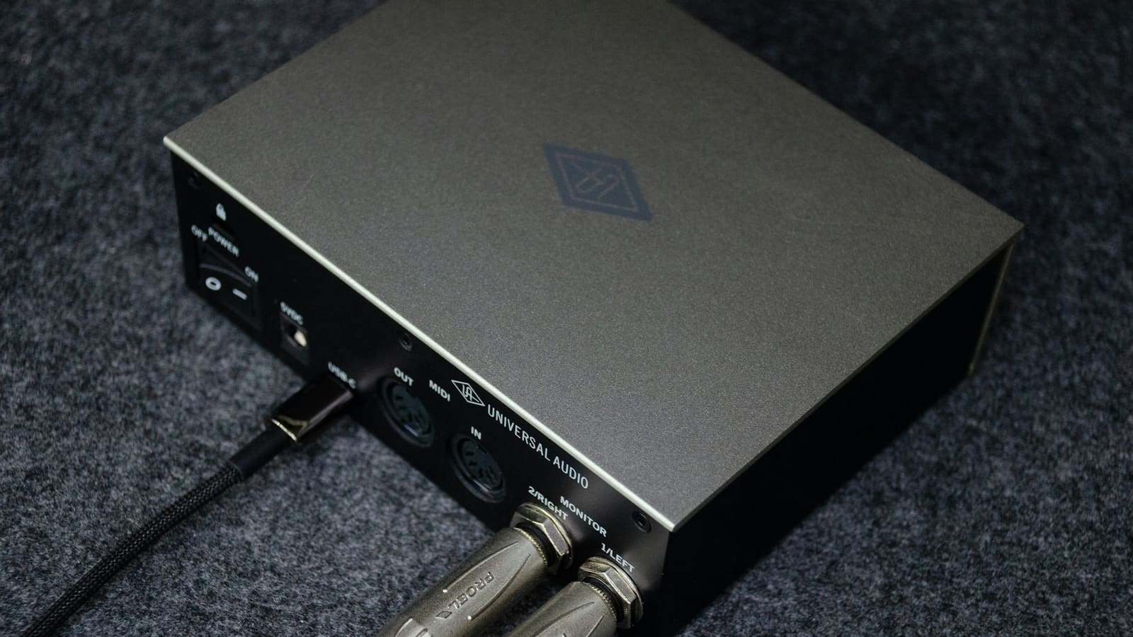 A small audio interface with cables plugged into its rear panel