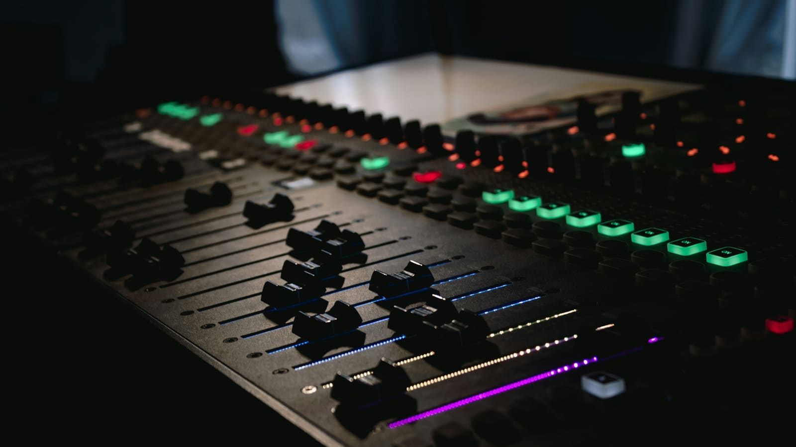 A mixing console with faders and illuminated channel controls
