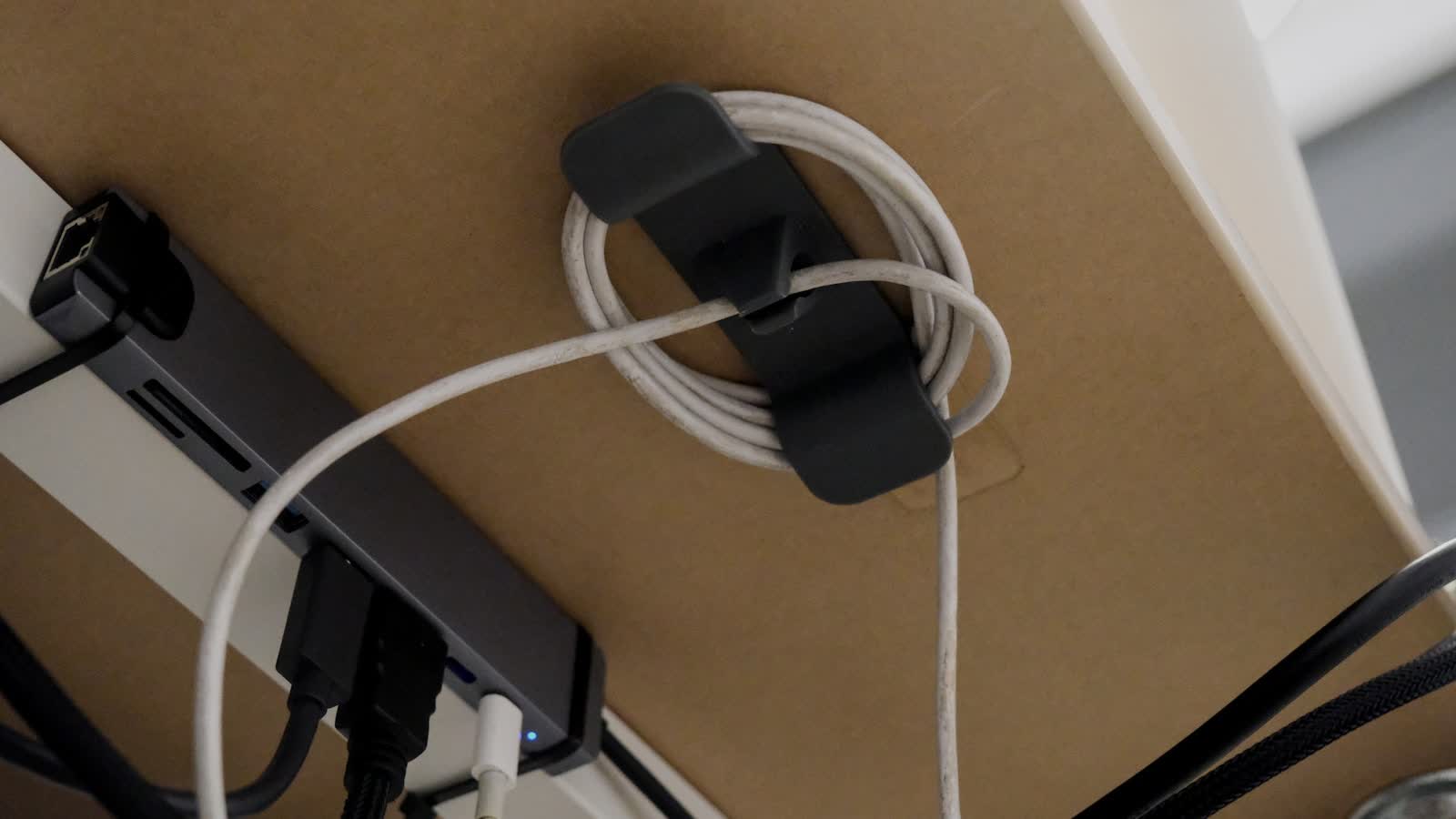 A USB hub and cables clipped to the underside of a desk