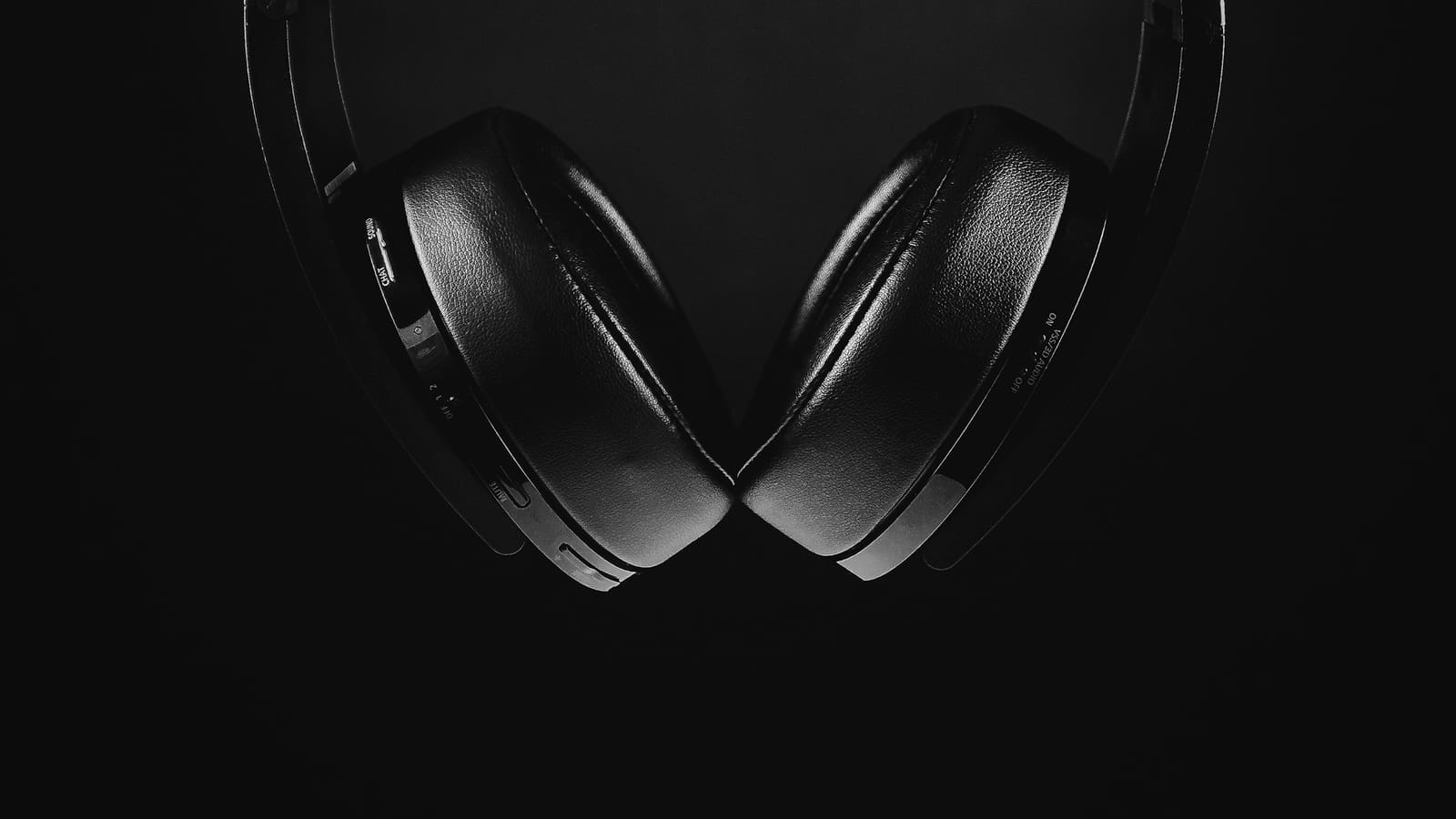 Two pairs of closed-back headphones on a dark surface