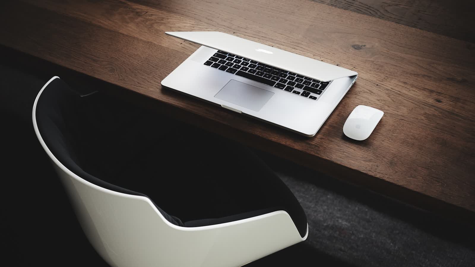A modern desk chair beside a desk with an open laptop