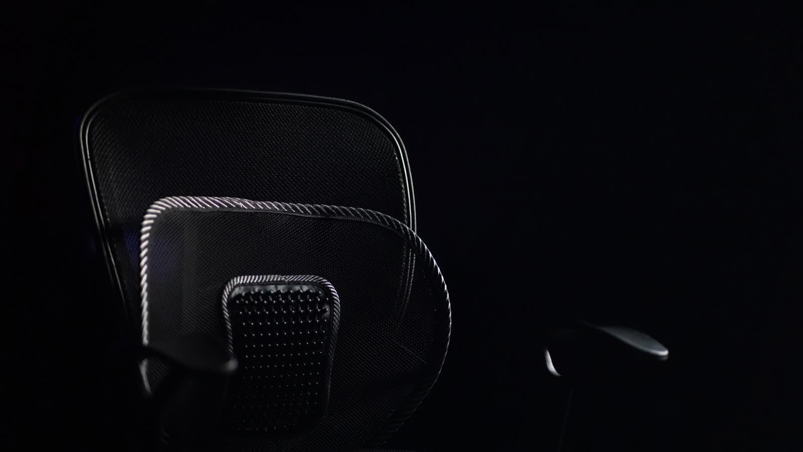 A mesh-backed office chair photographed against a dark background
