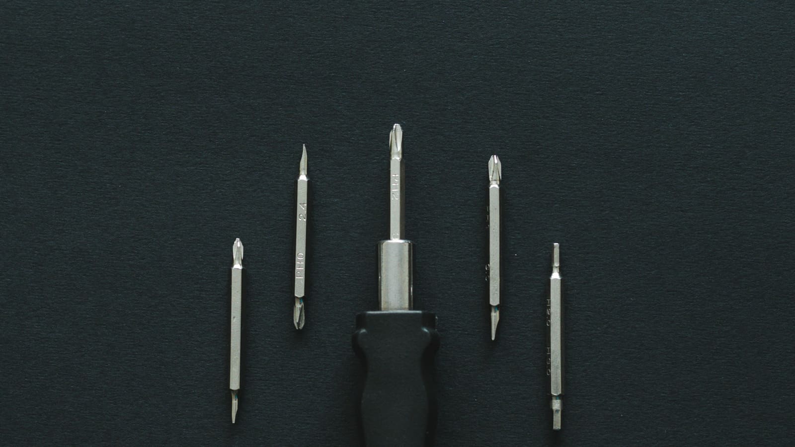 A set of precision screwdriver bits arranged on a dark surface