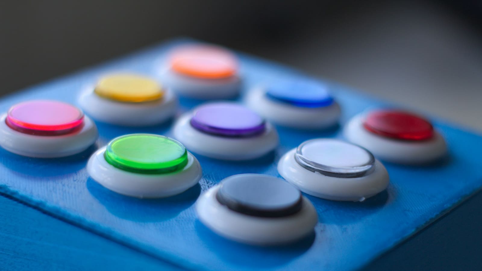 A row of large coloured arcade buttons on a panel