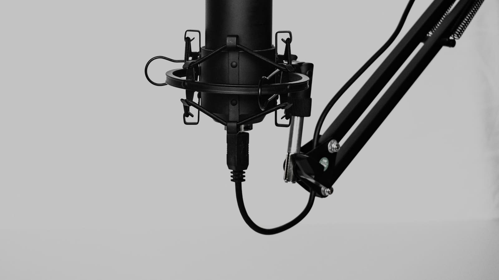 A condenser microphone in a shock mount on a boom arm