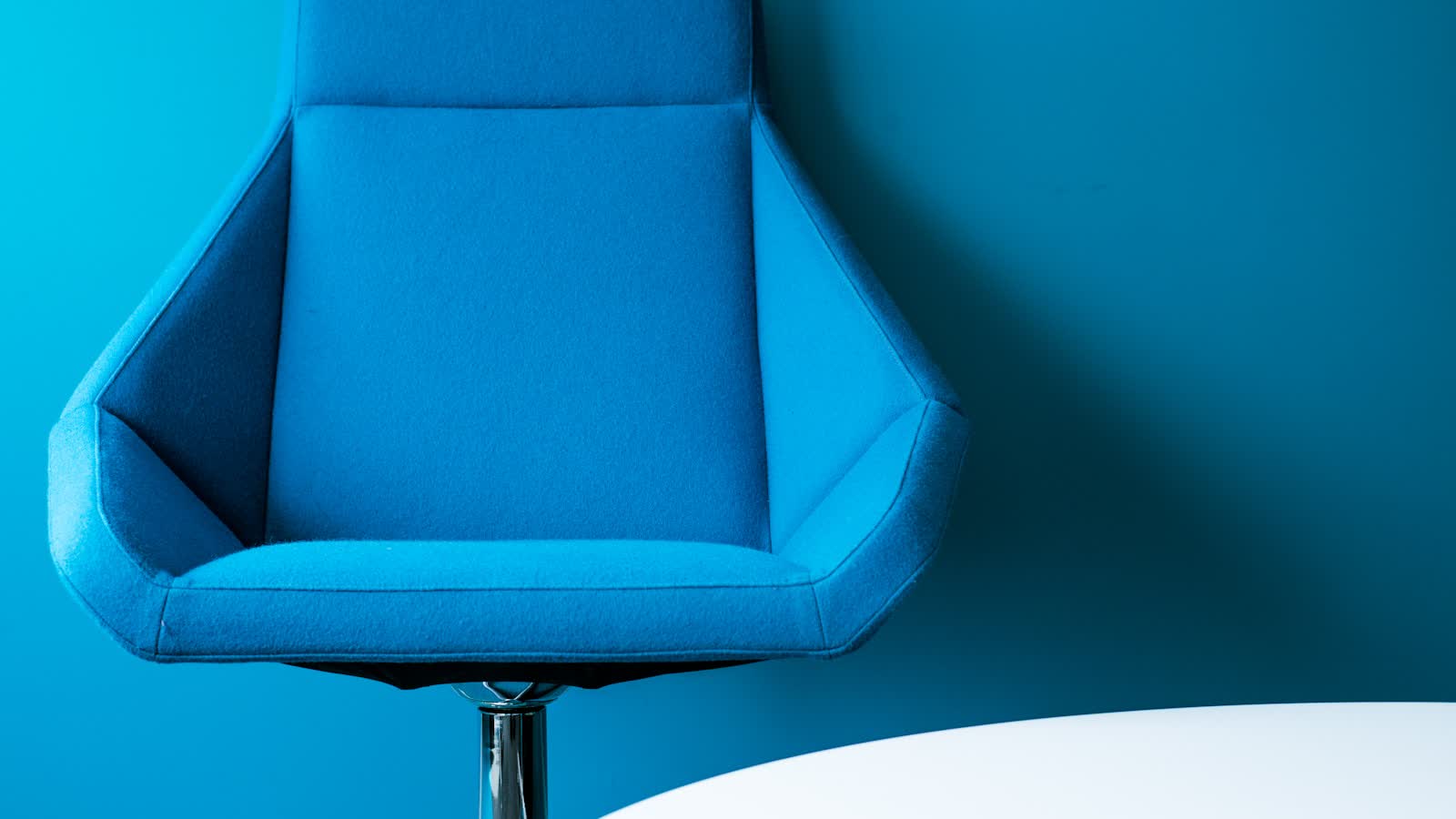 Close-up of a blue upholstered office chair against a blue background