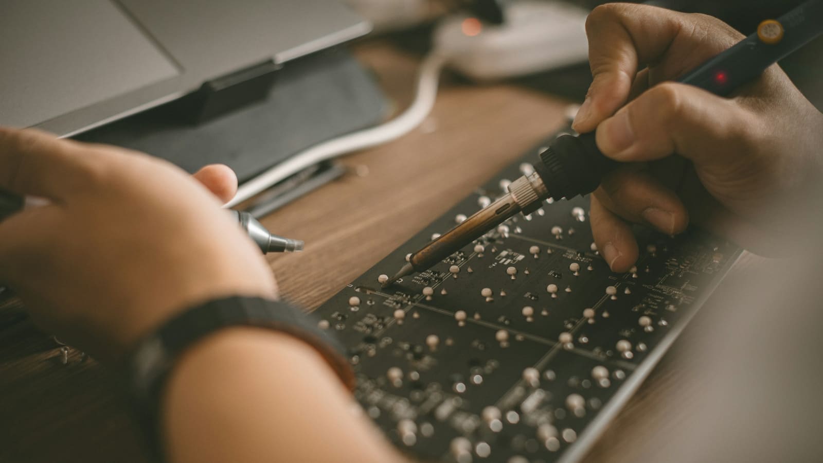 Hands working on a circuit board with a small screwdriver