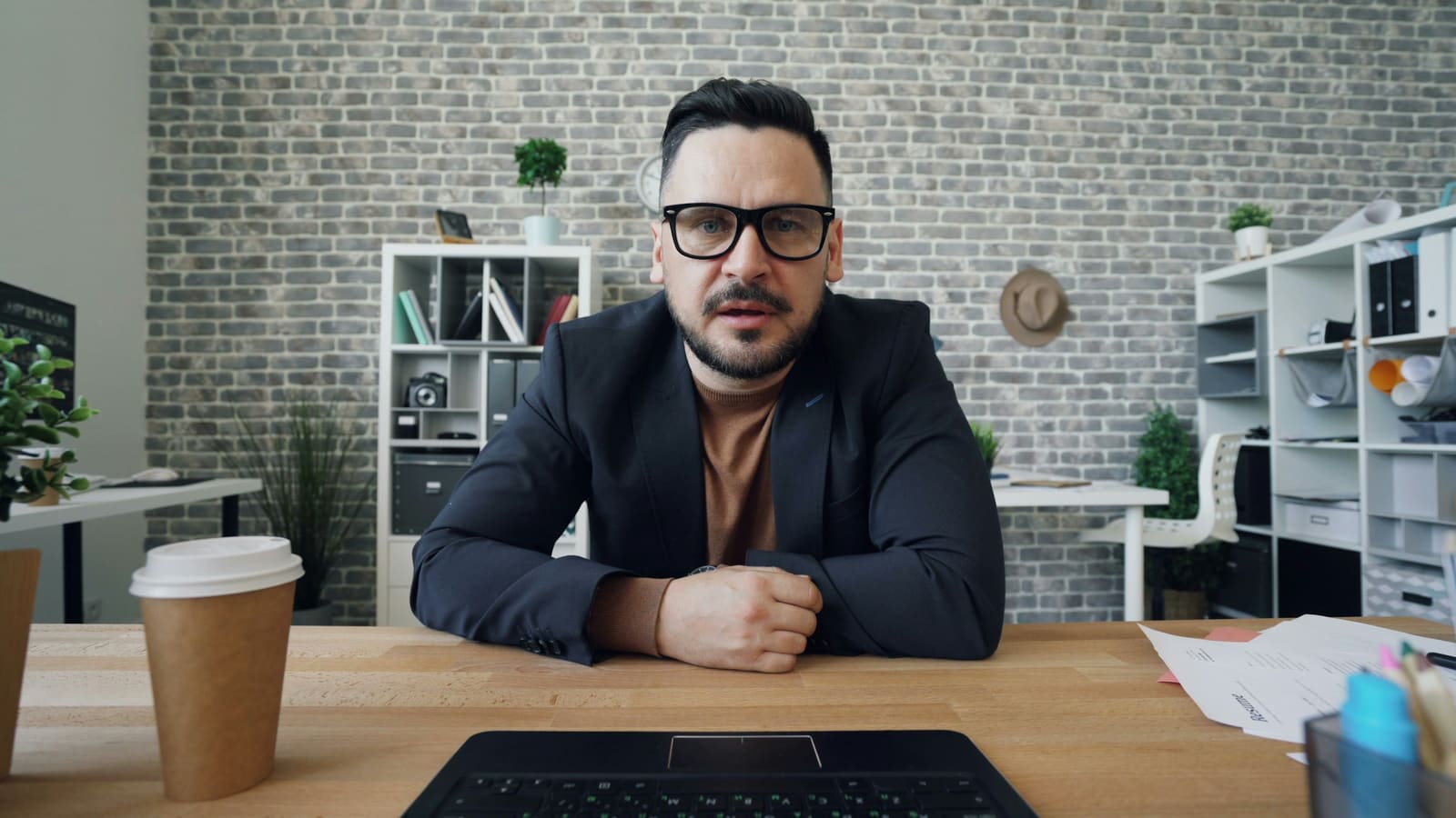 A person seated at a desk facing a camera in a lit room