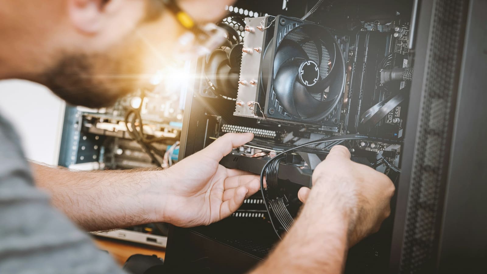 A person lowering a graphics card into a slot inside a computer