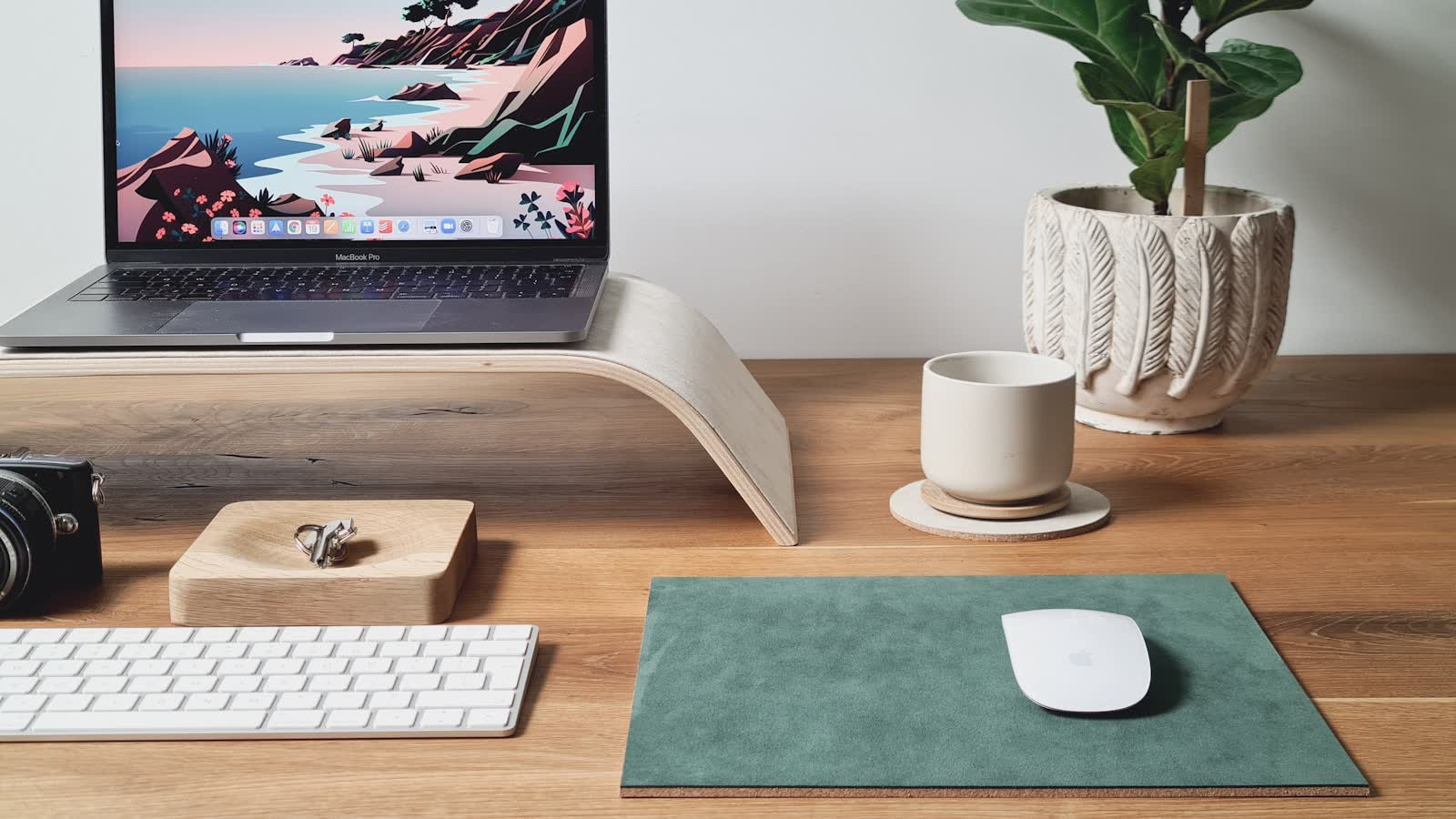 A laptop on a wooden riser with a separate keyboard and mouse