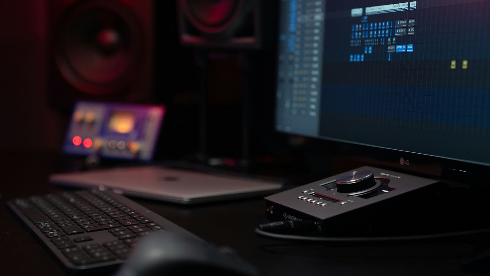 A recording desk with editing software open on a wide monitor