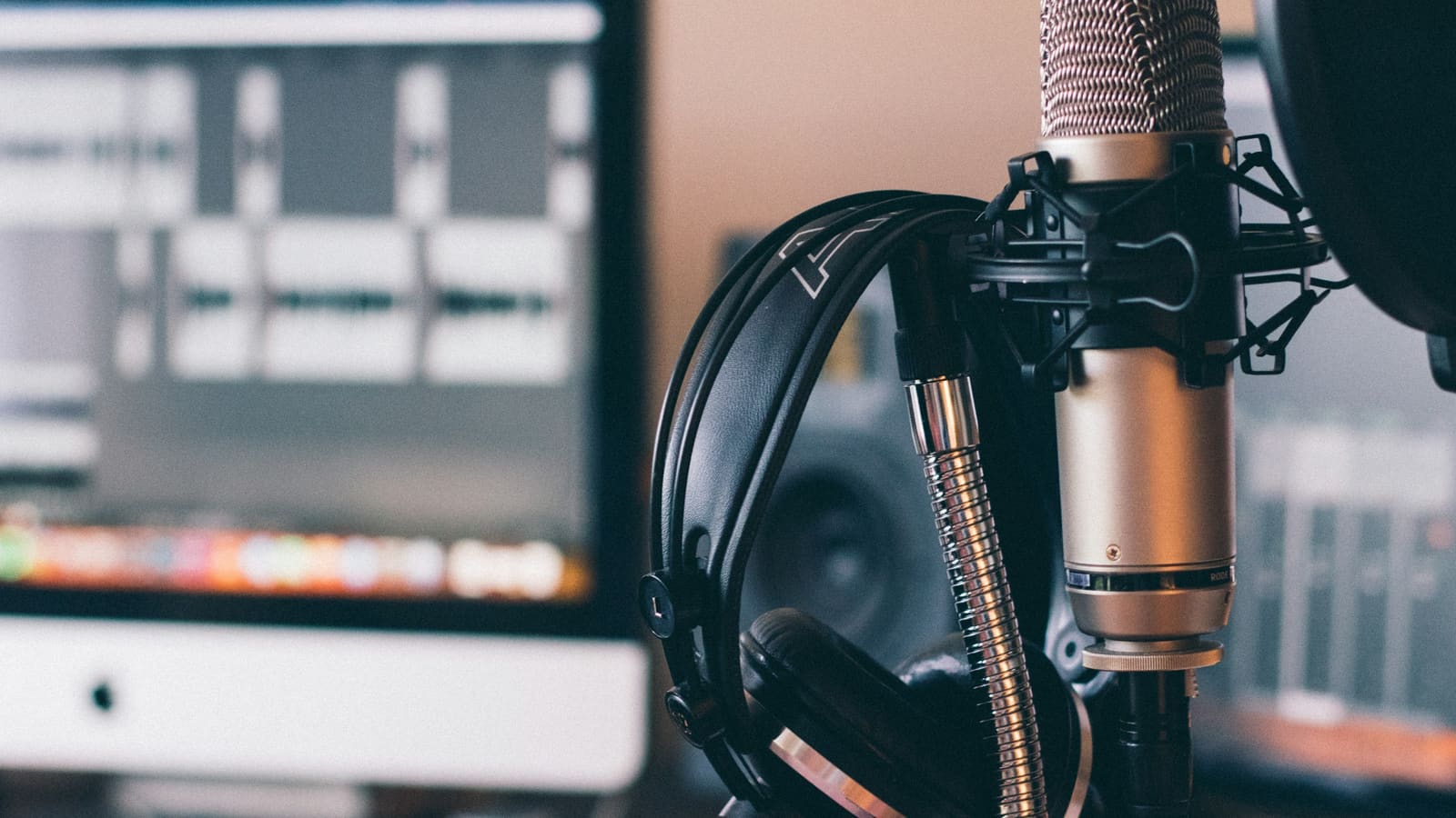 A desk with a microphone on an arm, headphones and a monitor
