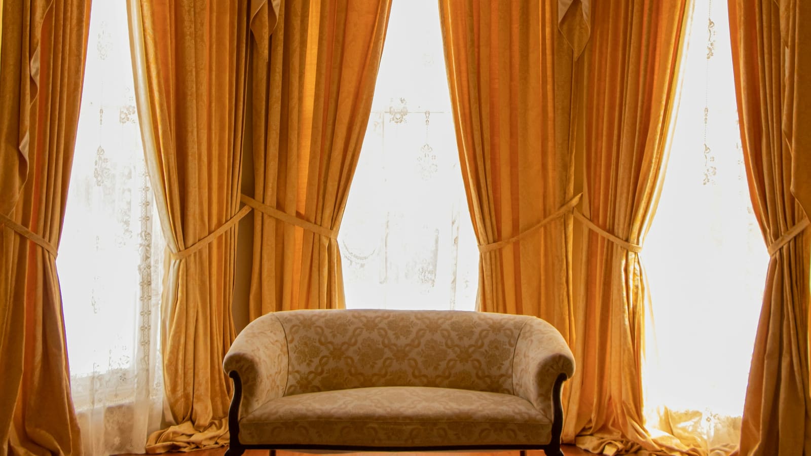 A room with heavy floor-length curtains and an upholstered sofa