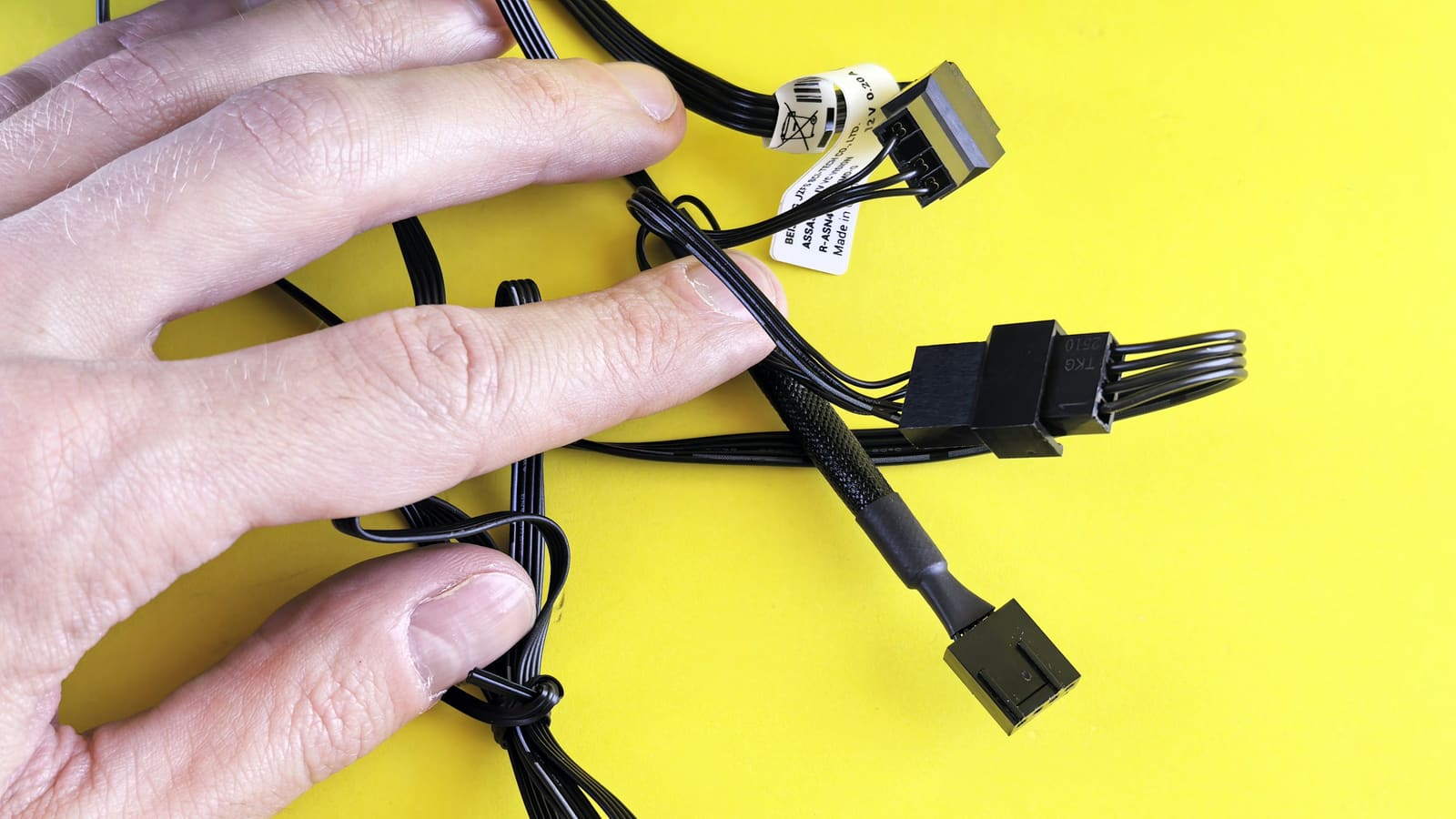 A hand sorting through a bundle of computer cables