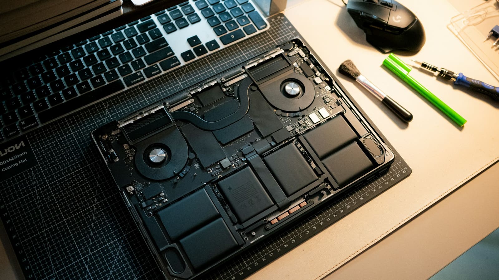 An opened computer with its components exposed and tools laid beside it