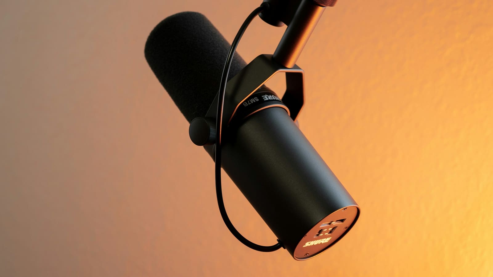 A broadcast dynamic microphone lit against a warm background