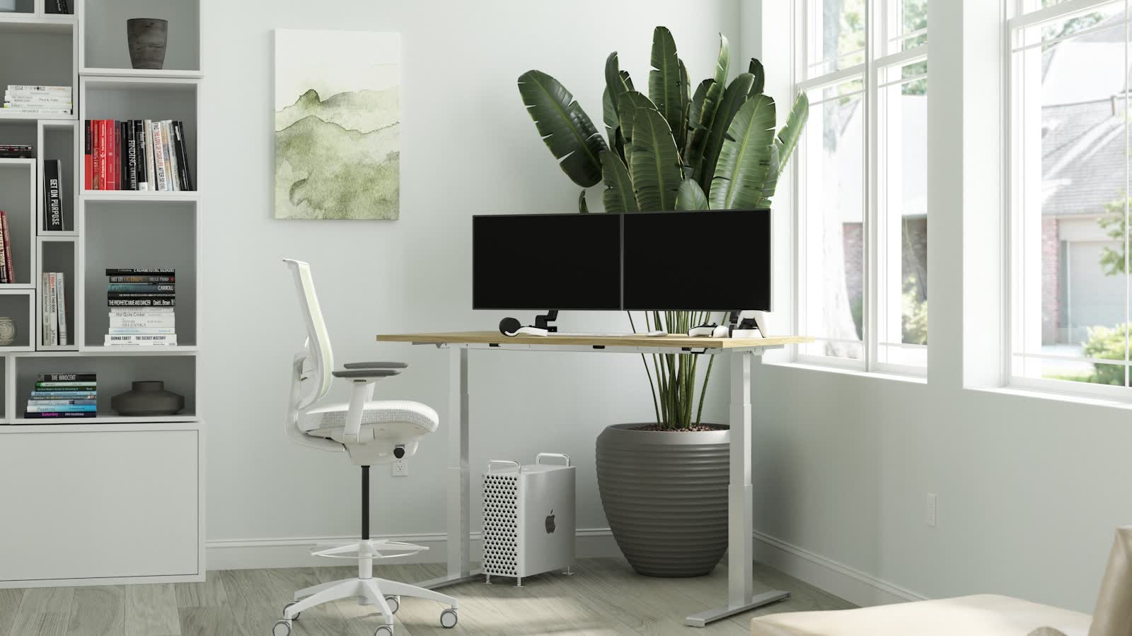 A white standing desk carrying two monitors in a bright room