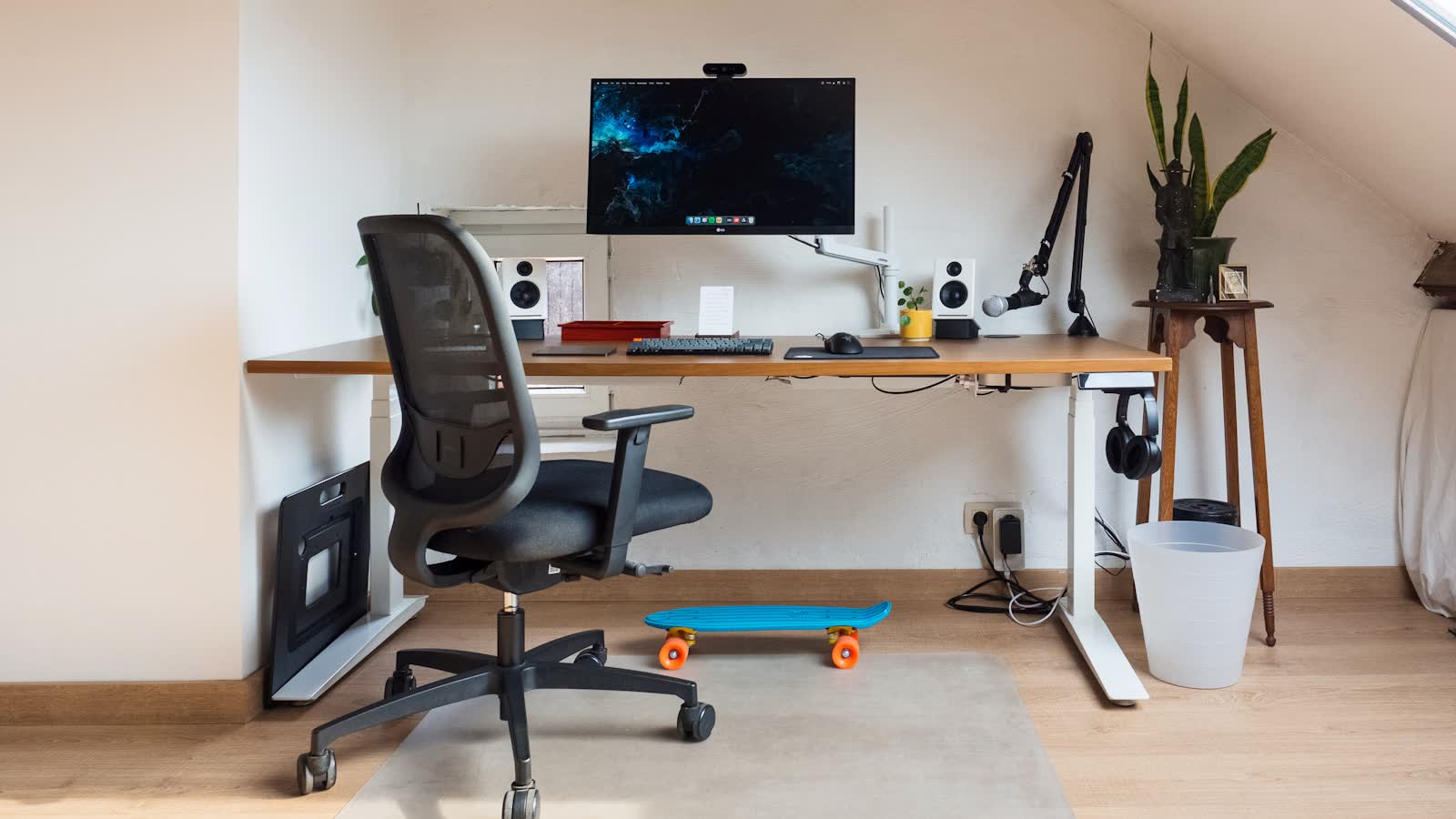 A home office under a sloped attic ceiling with a standing desk