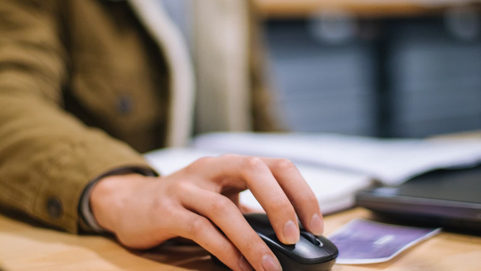 A hand resting on a mouse at a desk